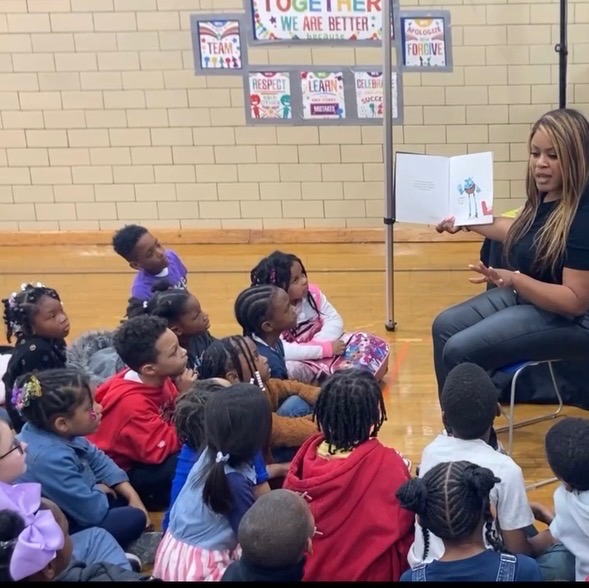 Children sitting together while a book is read aloud during a literacy activation.