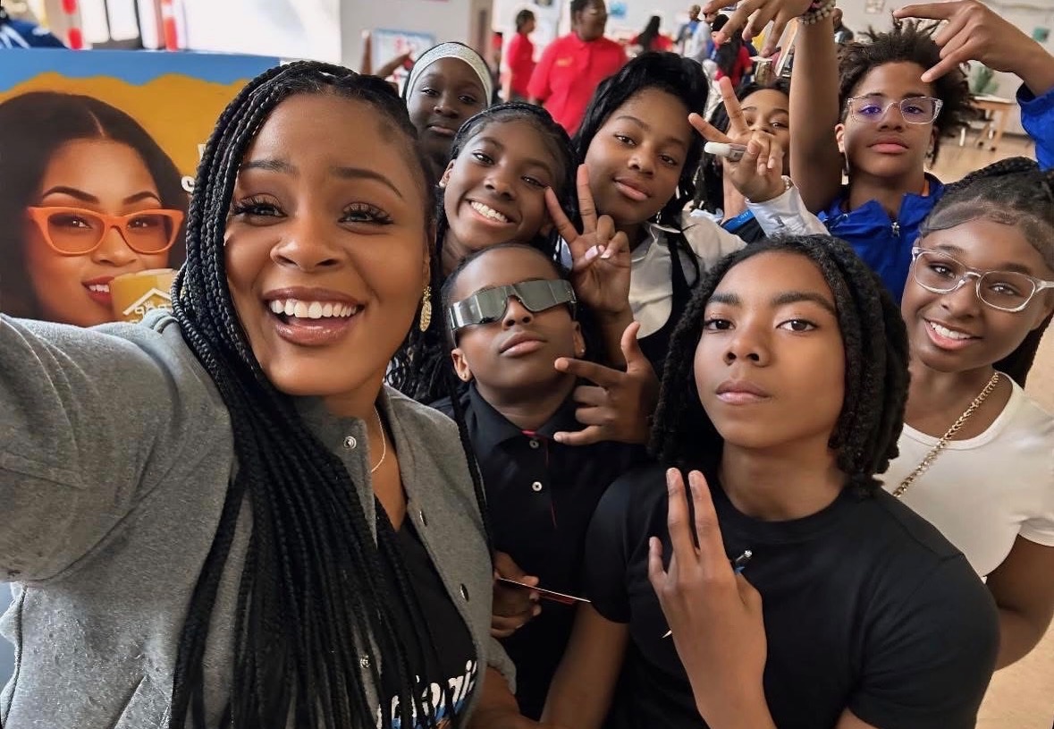 Tropikana smiling with a group of students at a youth event.